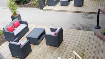 Una terraza con mobiliario exterior, incluyendo sofás, sillas y una mesa.
