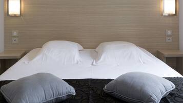Een hotelkamer met een groot bed, twee bedlampen en een hoofdeinde met een lamp.