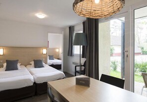 Une chambre d’hôtel avec deux lits, une table à manger, un lustre en osier et une vue sur l’extérieur.