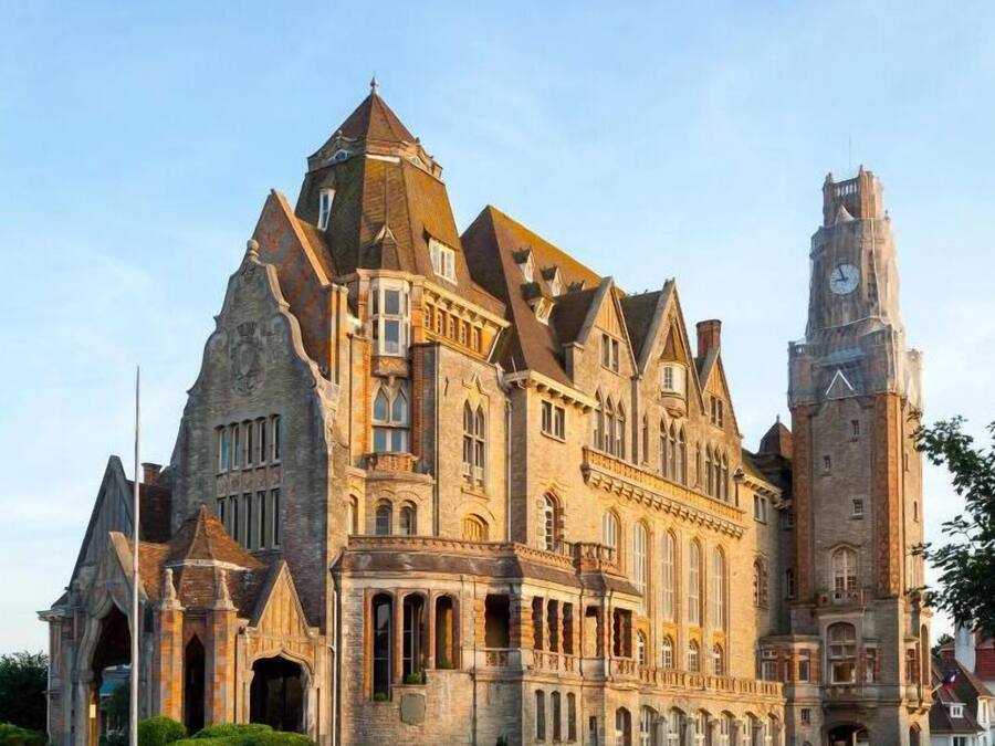 Un grand bâtiment historique, doté d’un imposant clocher et de plusieurs toits en forme de pyramide.