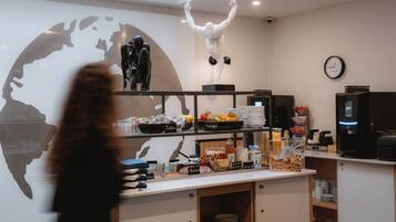 A modern interior with a counter displaying food items, a world map mural, and a clock on the wall.