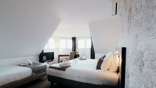A hotel room with two beds, a desk, a TV, and a window with curtains. - Hôtel Red Fox (Le Touquet-Paris-Plage)