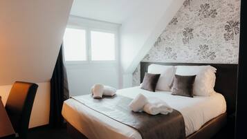 A hotel room with a neatly made bed, a chair, and a large window.