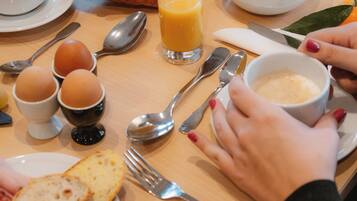 A breakfast table with croissants, eggs, bread, cheese, and a bowl of cereal.