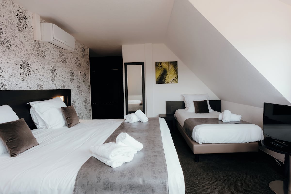 A modern hotel room with two beds, a flat-screen TV, and a large mirror.