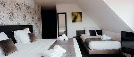 A modern hotel room with two beds, a flat-screen TV, and a large mirror.