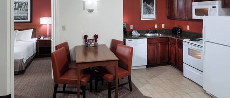 Habitación de hotel con comedor, kitchenette y una cama.