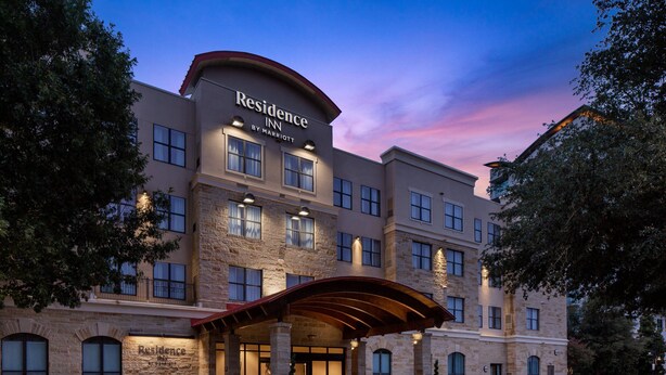 Un hotel de varios pisos con fachada de piedra, un acceso cubierto y un letrero que dice "Residence Inn by Marriott".