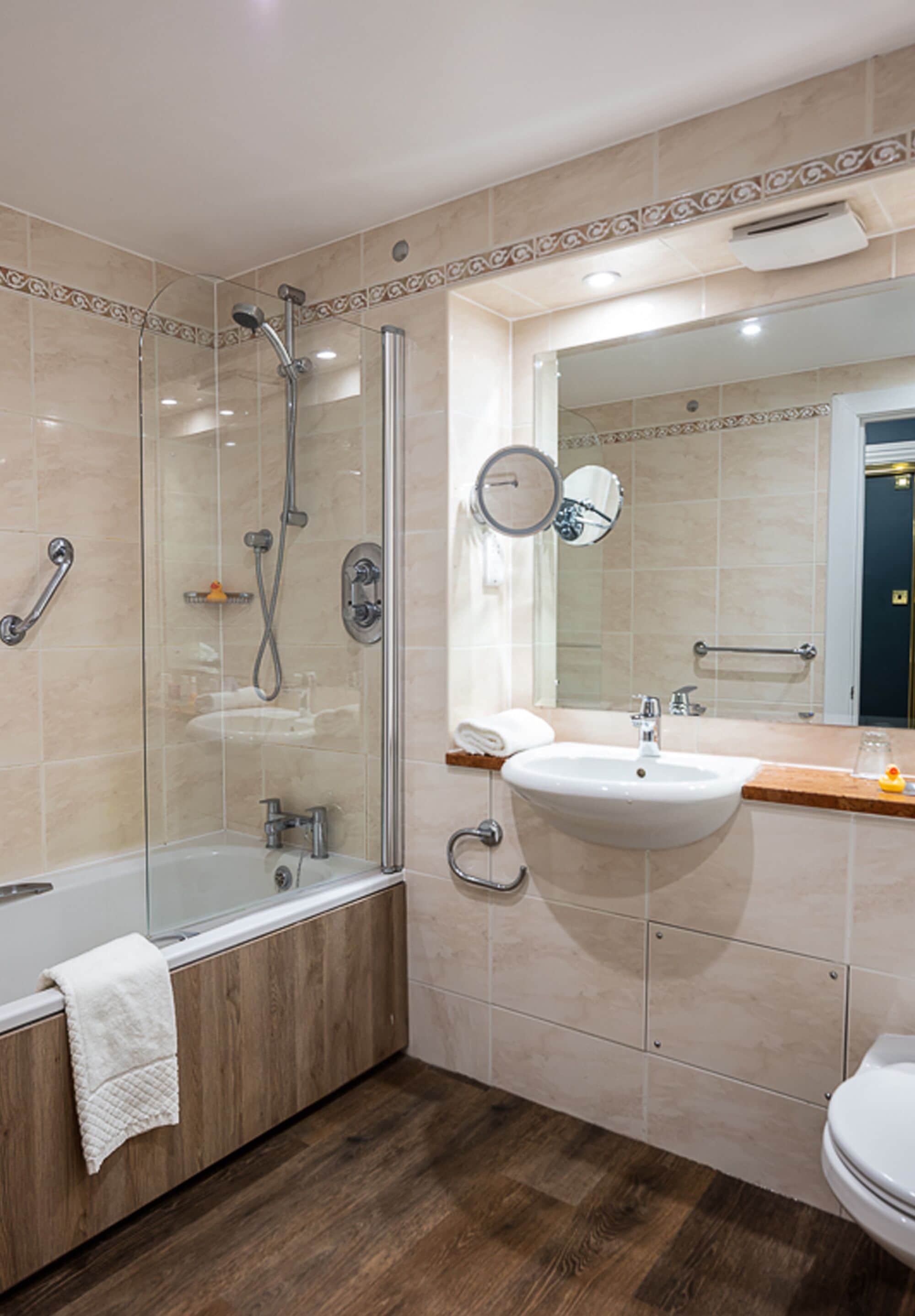 A modern bathroom with a glass-enclosed shower, a wooden vanity with a sink, and a toilet.