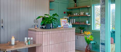 A reception area with a wooden desk, a pink reception desk, and a large window.