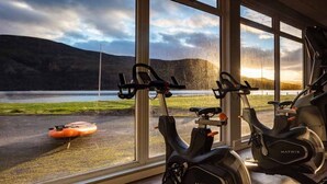 A gym with stationary bikes and a rowing machine, large windows with a view of a lake and mountains. - Loch Rannoch Hotel and Spa (Pitlochry)