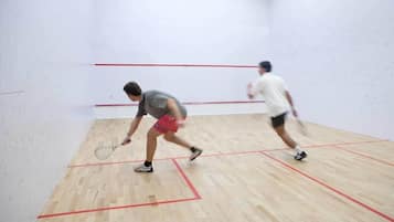 A squash court with wooden flooring and red boundary lines.