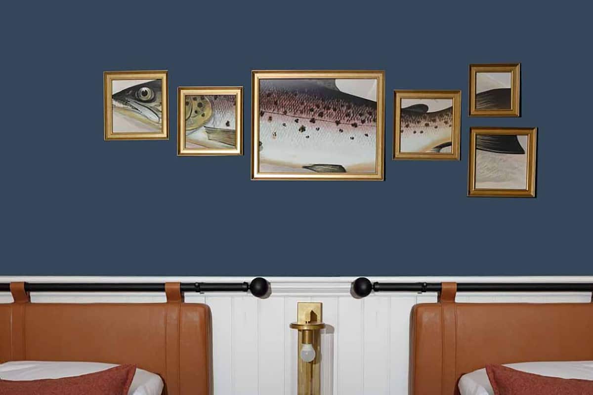 Une chambre d’hôtel avec un lit, une table de chevet et un mur orné de tableaux.