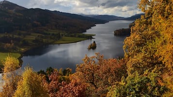 Un lago rodeado de árboles y colinas con colores otoñales.