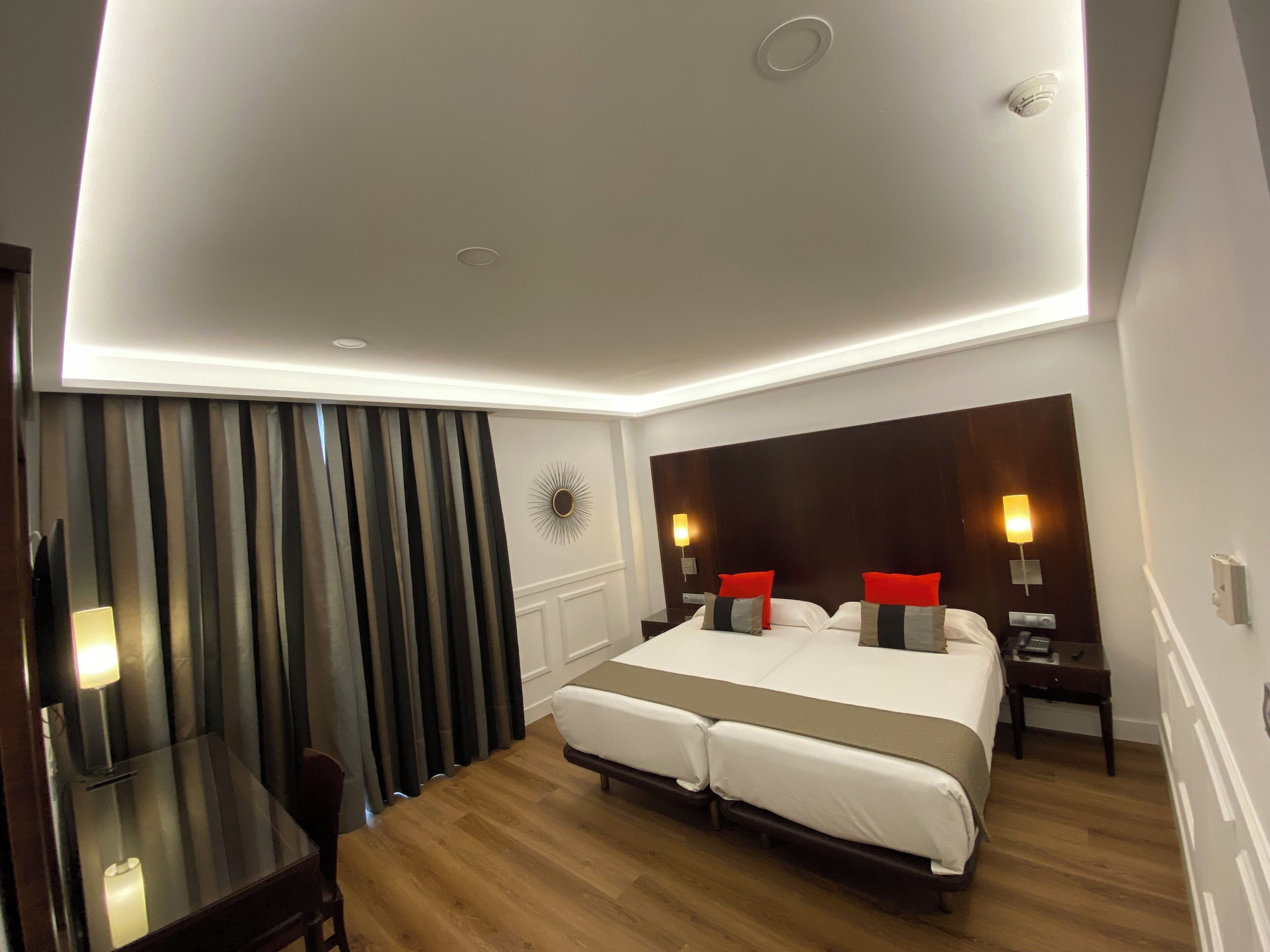A hotel room with a large bed, bedside tables, a desk, and a chair.