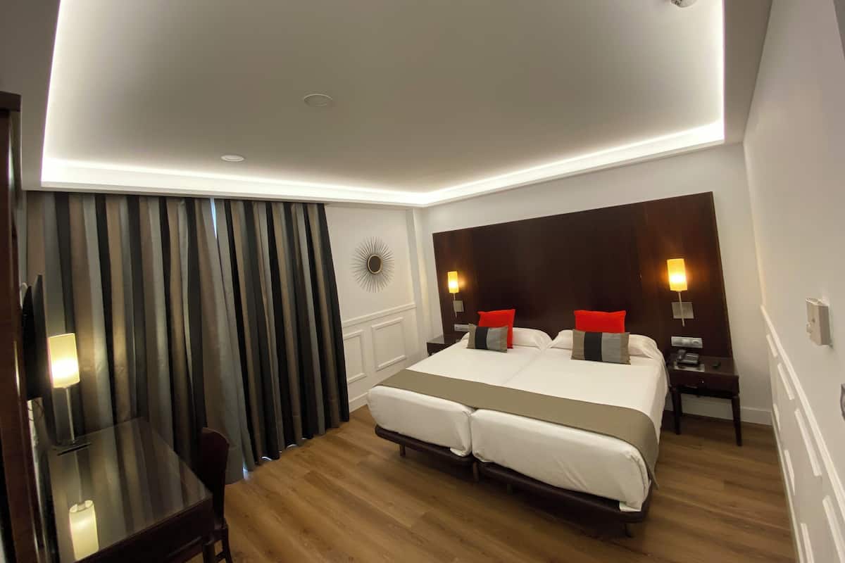 Habitació d'hotel amb un llit gran, taules de nit, escriptori i una cadira.