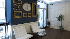 Una zona d'entrada amb una paret blava, miralls amb marc daurat i un sofà blanc.
