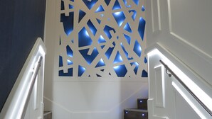 Una escala de fusta amb baranes blanques que condueix a una habitació amb un mur decoratiu d'entramat blau.