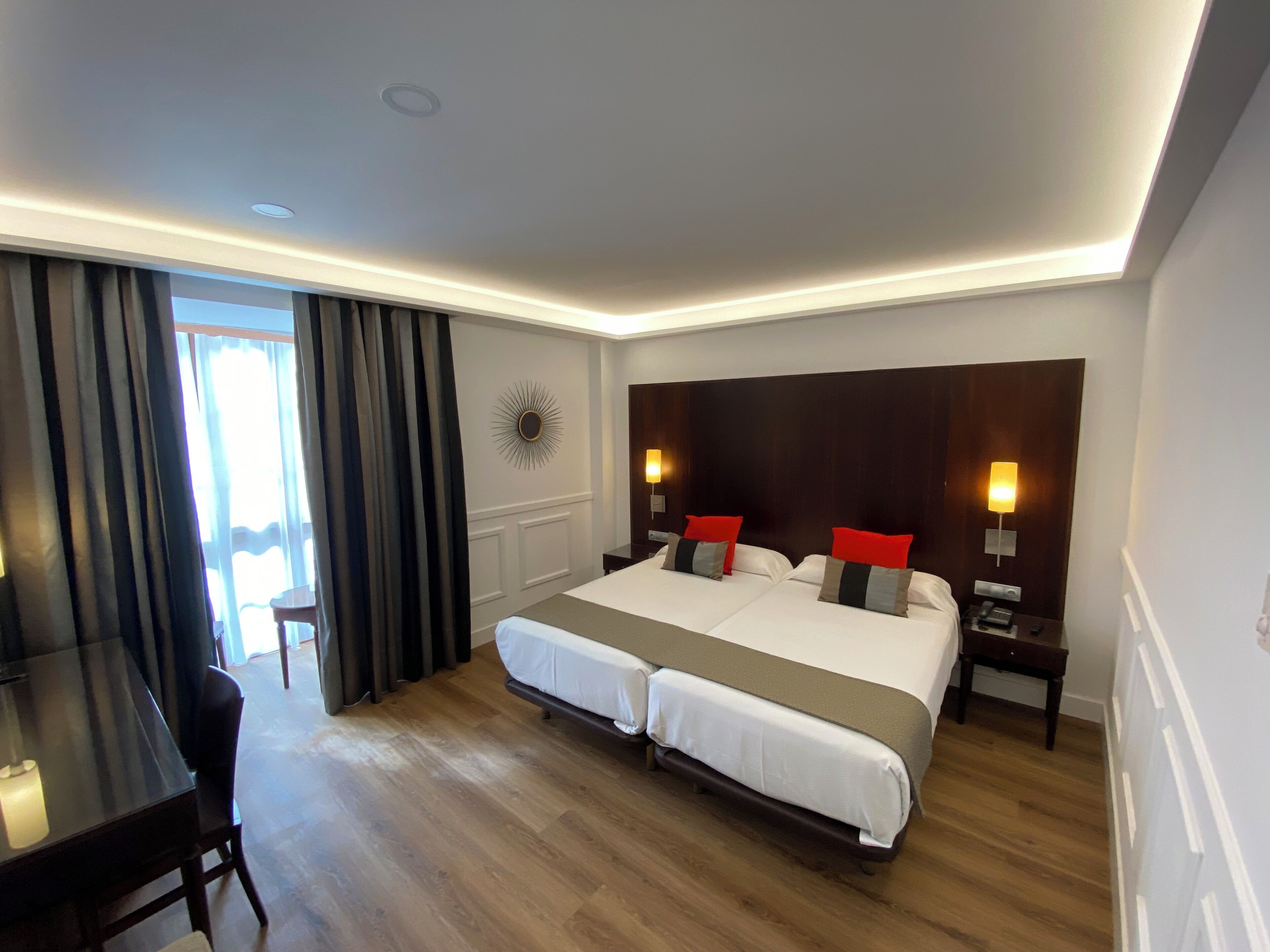 A hotel room with a large bed, two bedside tables, a desk, and a chair.
