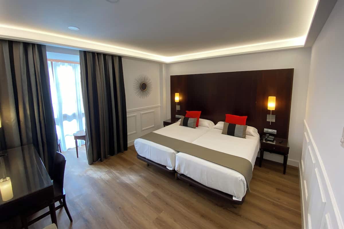 Habitació d'hotel amb un llit gran, dues taules de nit, un escriptori i una cadira.
