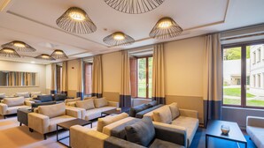 Un hall d’hôtel doté de plusieurs canap és, d’une table basse et de luminaires suspendus.