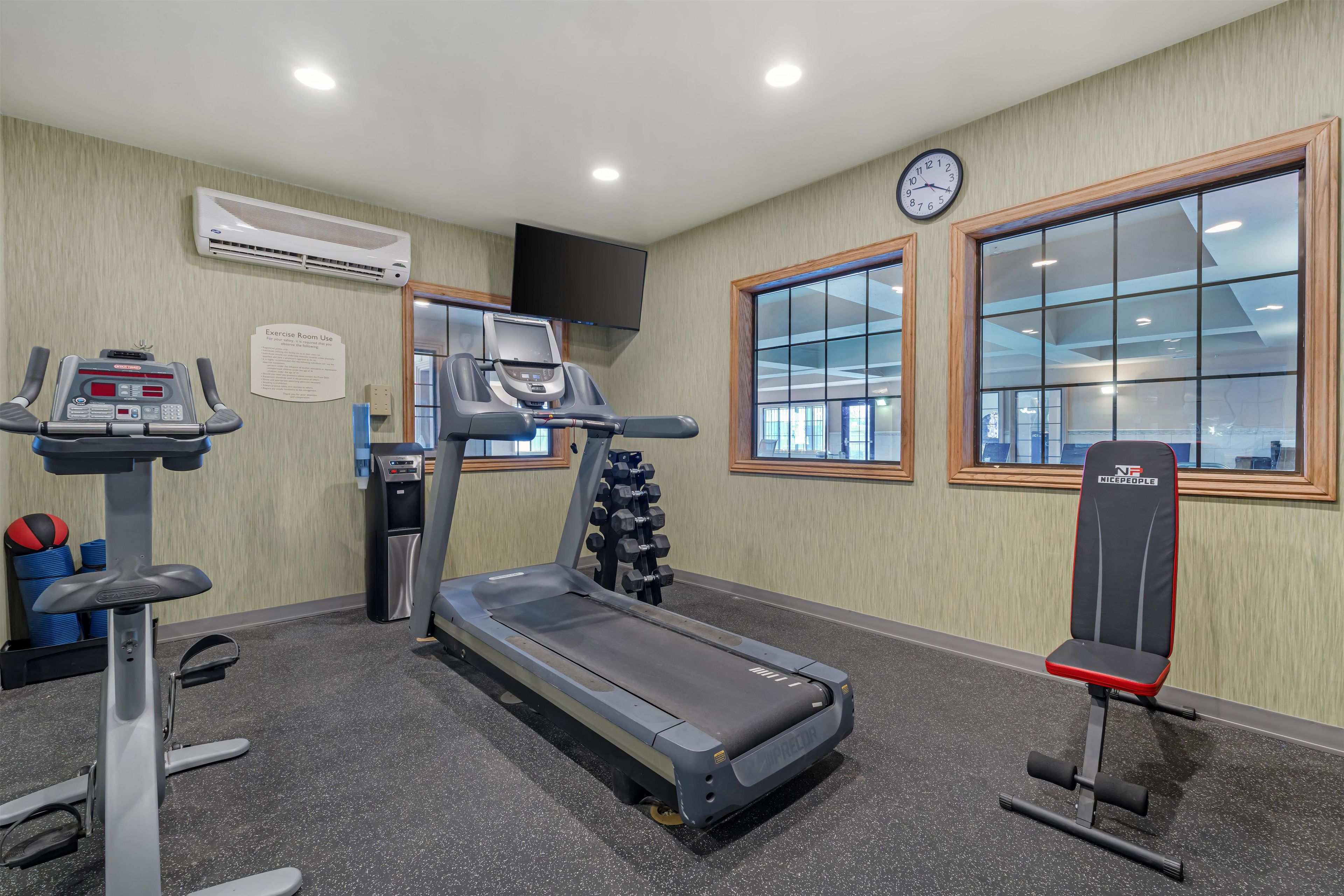 Un gimnasio con cinta de correr, banco para pesas y equipamiento de ejercicio.