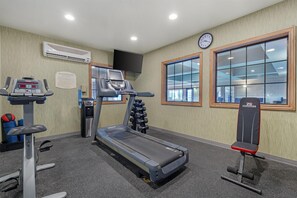 Un gimnasio con cinta de correr, banco para pesas y equipamiento de ejercicio.