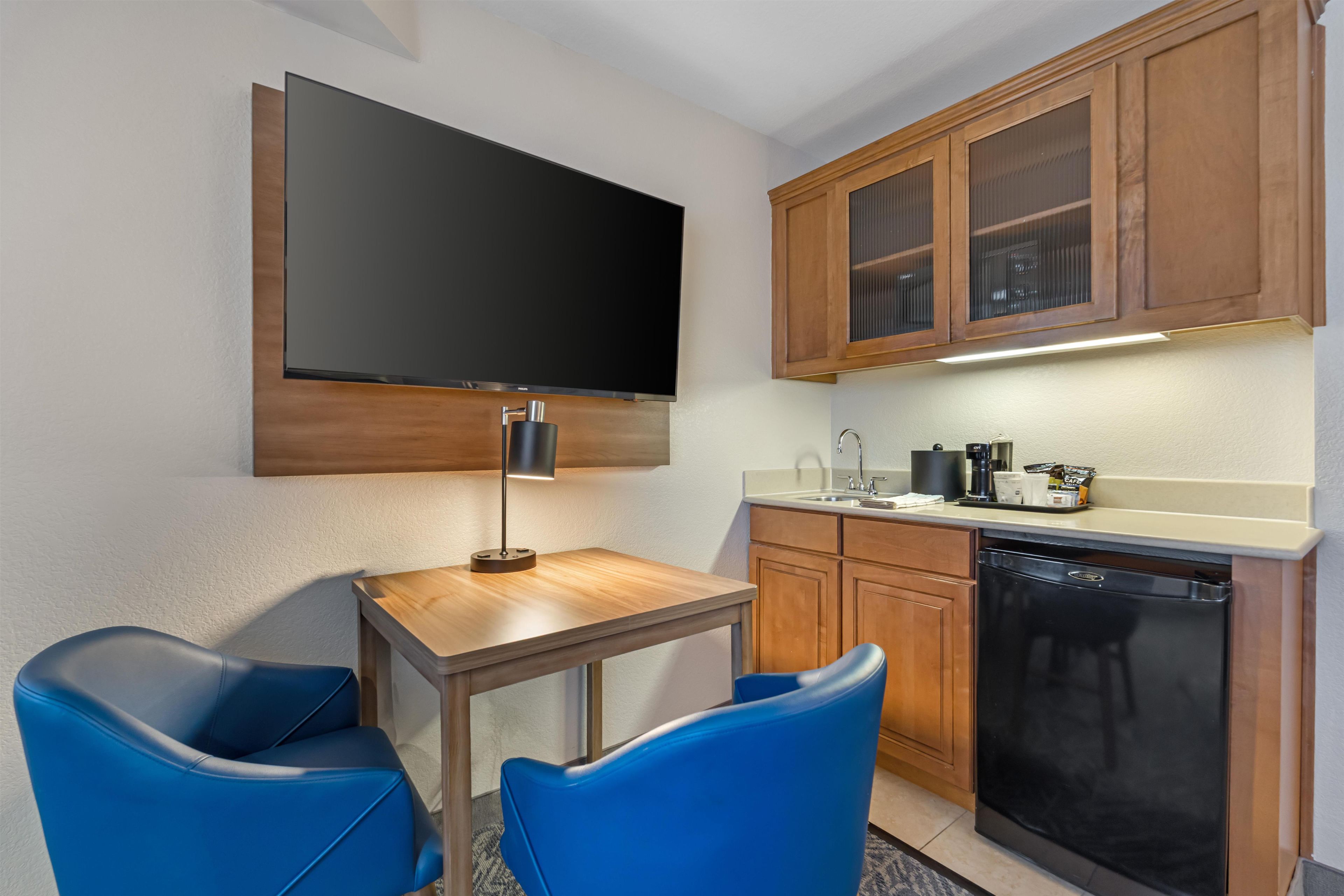 A compact kitchen with a flat-screen TV, a coffee maker, and a dishwasher.