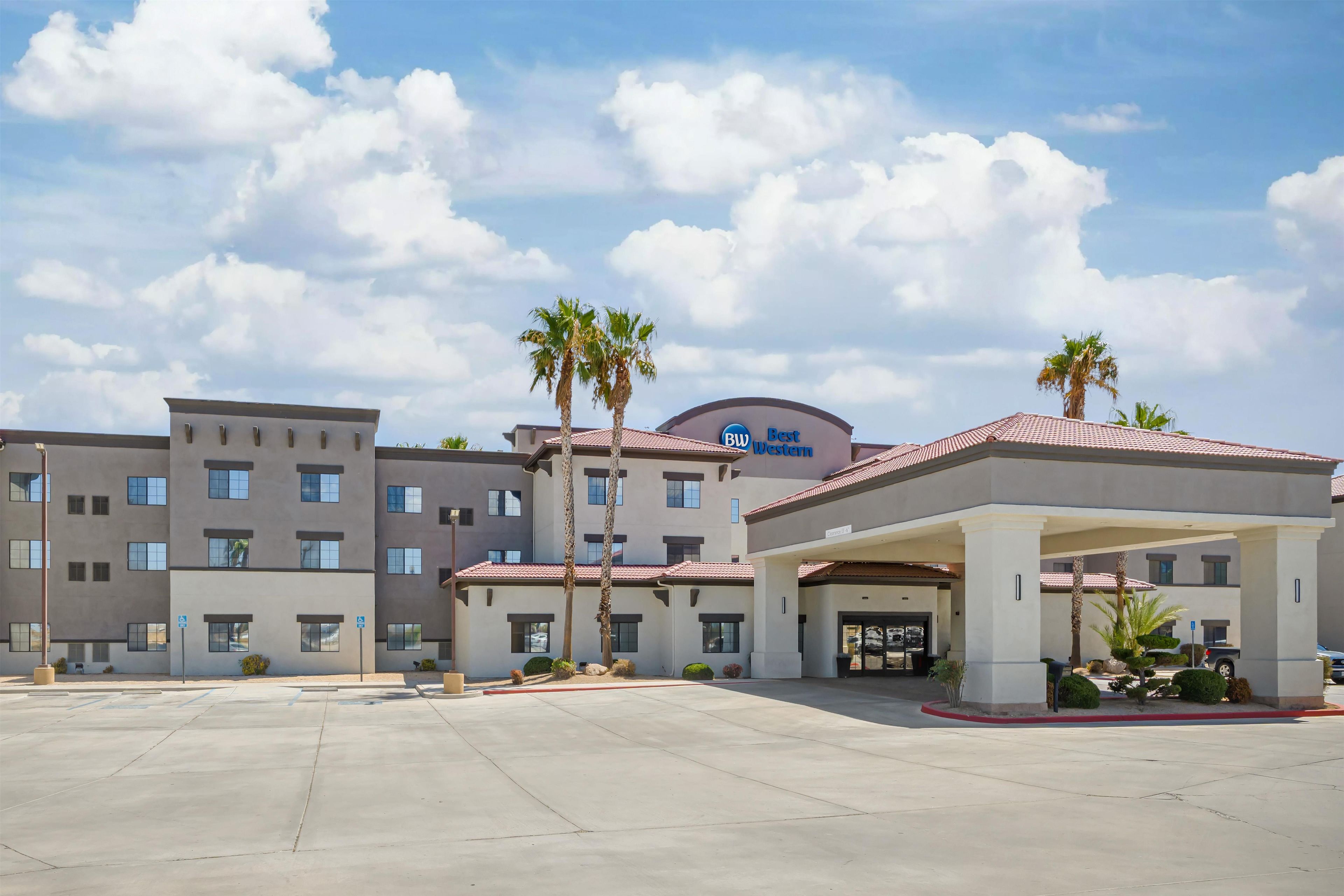 Un hotel de diseño moderno, con un edificio central que muestra el letrero 'Best Western', varios pisos y un área de entrada cubierta.