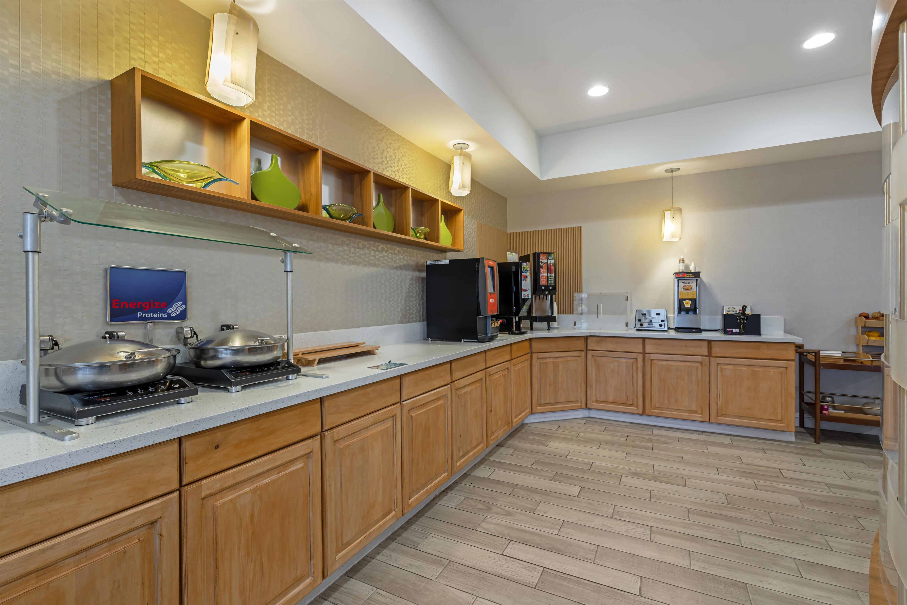 Una cocina moderna con armarios de madera, una estufa de acero inoxidable y un estante de vidrio con adornos.