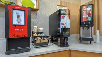 Una estación de café con una cafetera, un dispensador de bebidas y un portavasos.