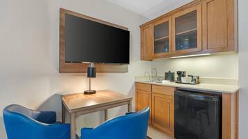 Una cocina compacta con televisión de pantalla plana, cafetera y lavavajillas.