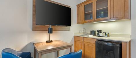 A compact kitchen with a flat-screen TV, a coffee maker, and a dishwasher.