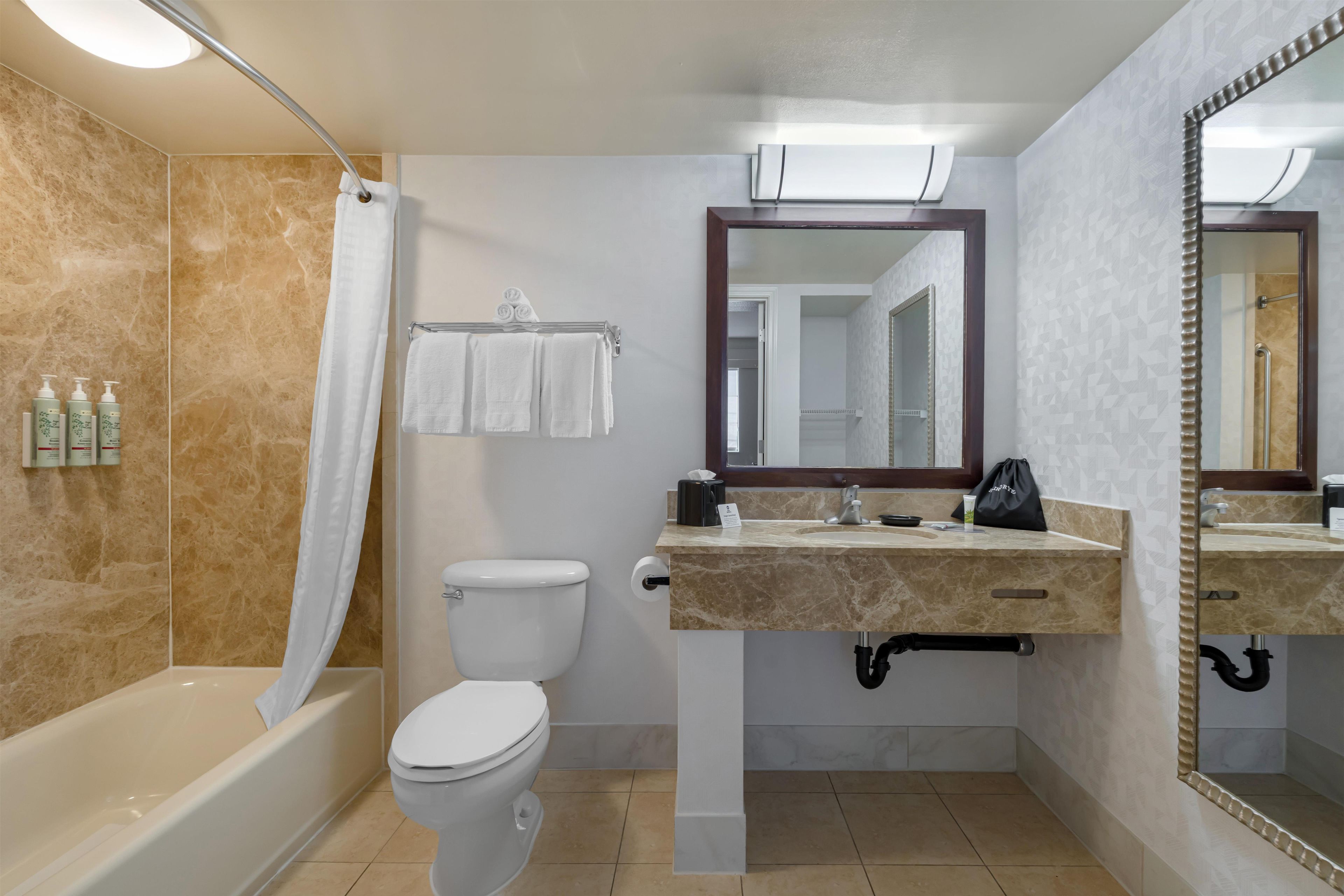Un baño moderno con bañera, inodoro y tocador con espejo.
