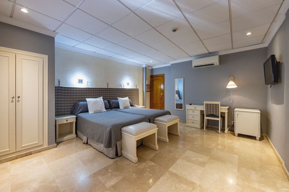 A bedroom with a large bed, bedside tables, a desk, and a chair.