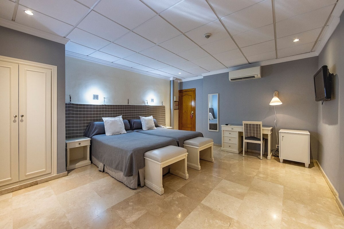 A modern bedroom with a large bed, two bedside tables, a desk, and a chair.