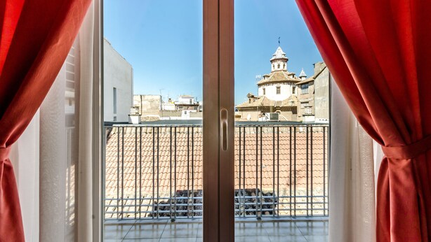 A view from a balcony with metal railings and a tiled floor, overlooking a building with a dome and a tower. - Sacromonte Hotel (Granada)