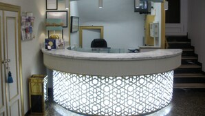 A reception area with a curved counter, a reception desk, and a staircase in the background. - Sacromonte Hotel (Granada)