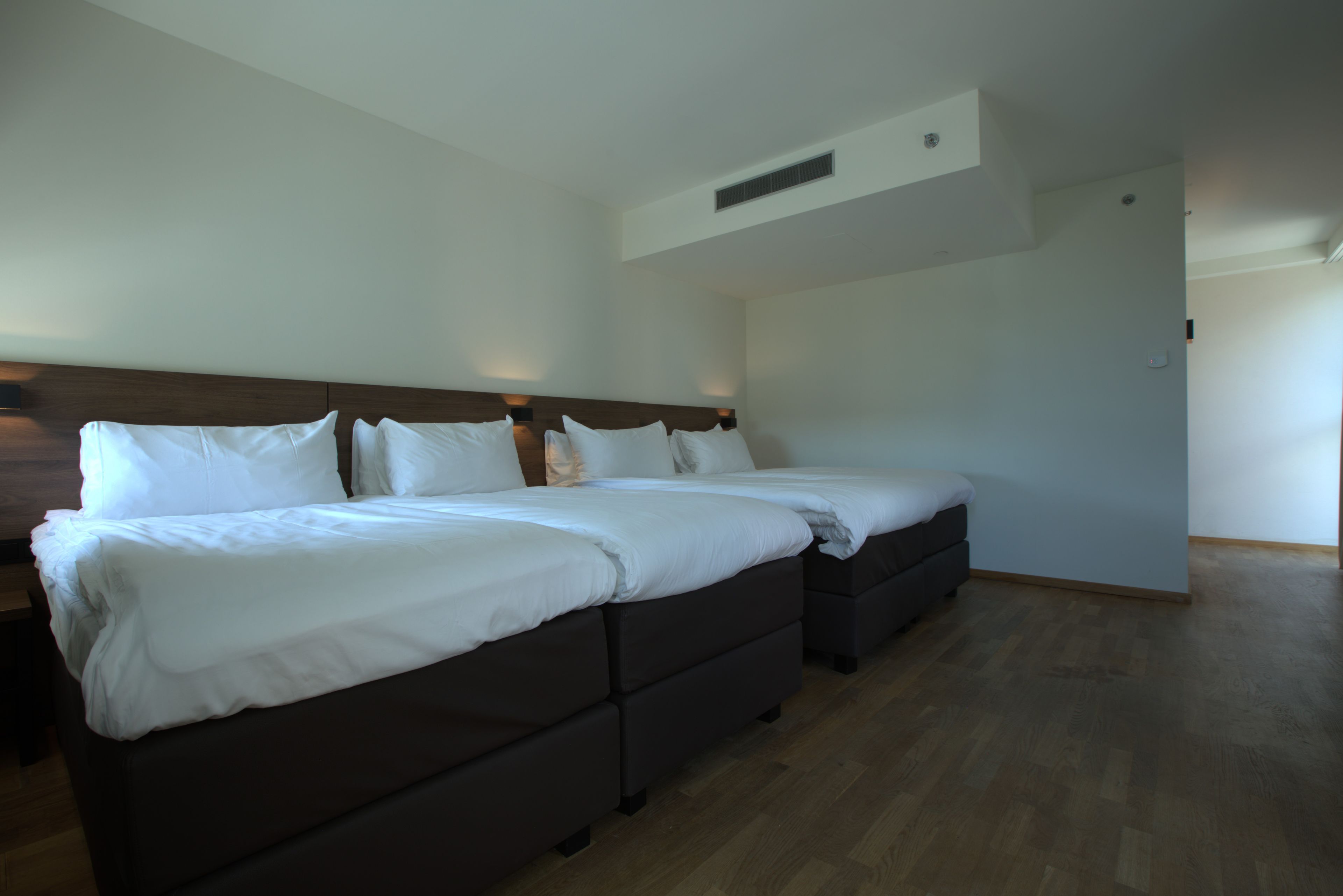 Una habitación de hotel con una cama grande, una mesita de noche y un armario.
