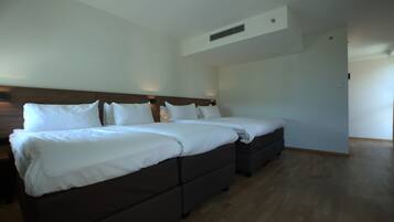 Una habitación de hotel con una cama grande, una mesita de noche y un armario.