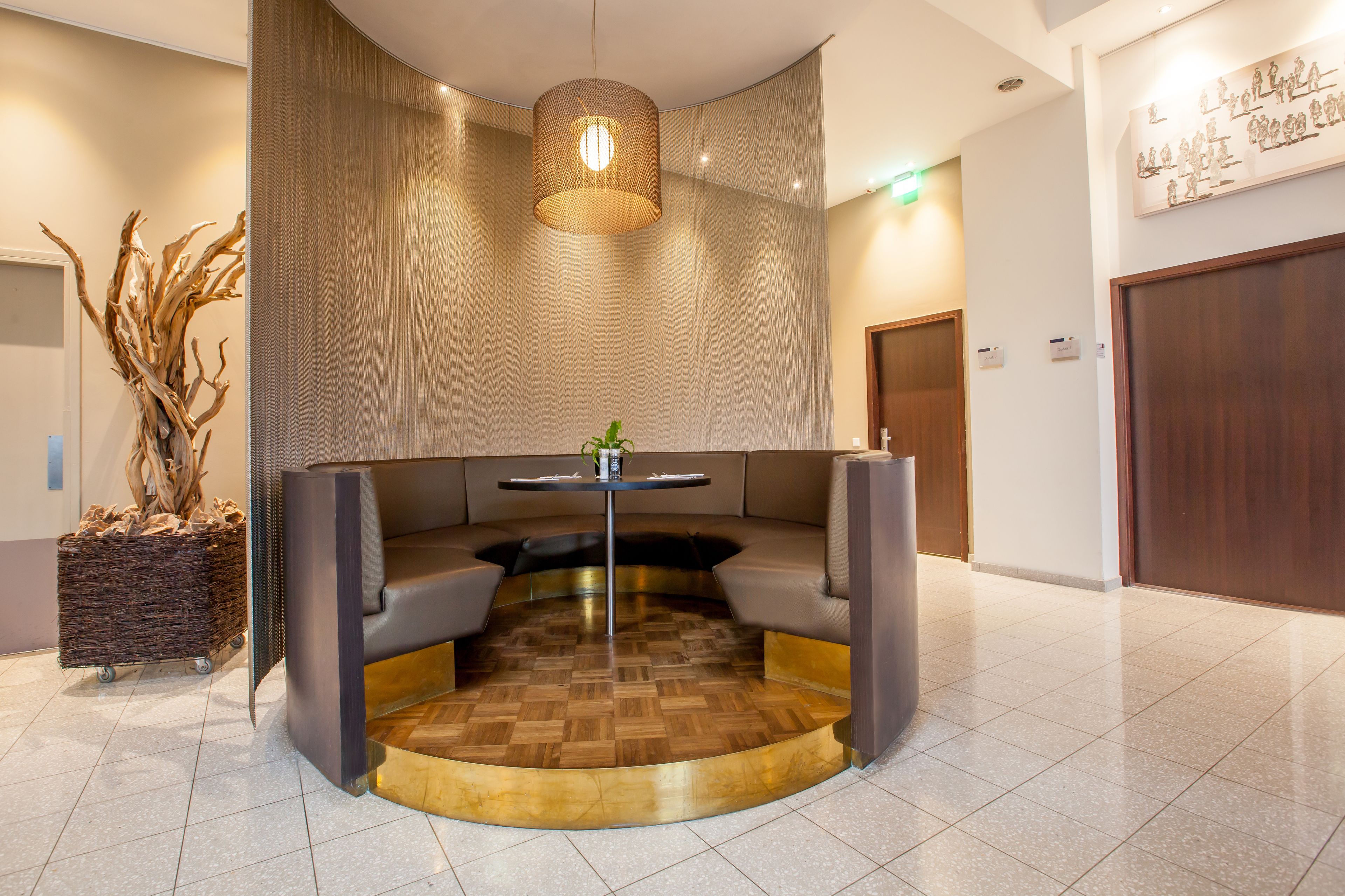 A modern lobby with a round seating area, a central table, and a decorative plant.