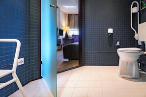 A bathroom with a toilet, a shower, a sink, and a mirror.