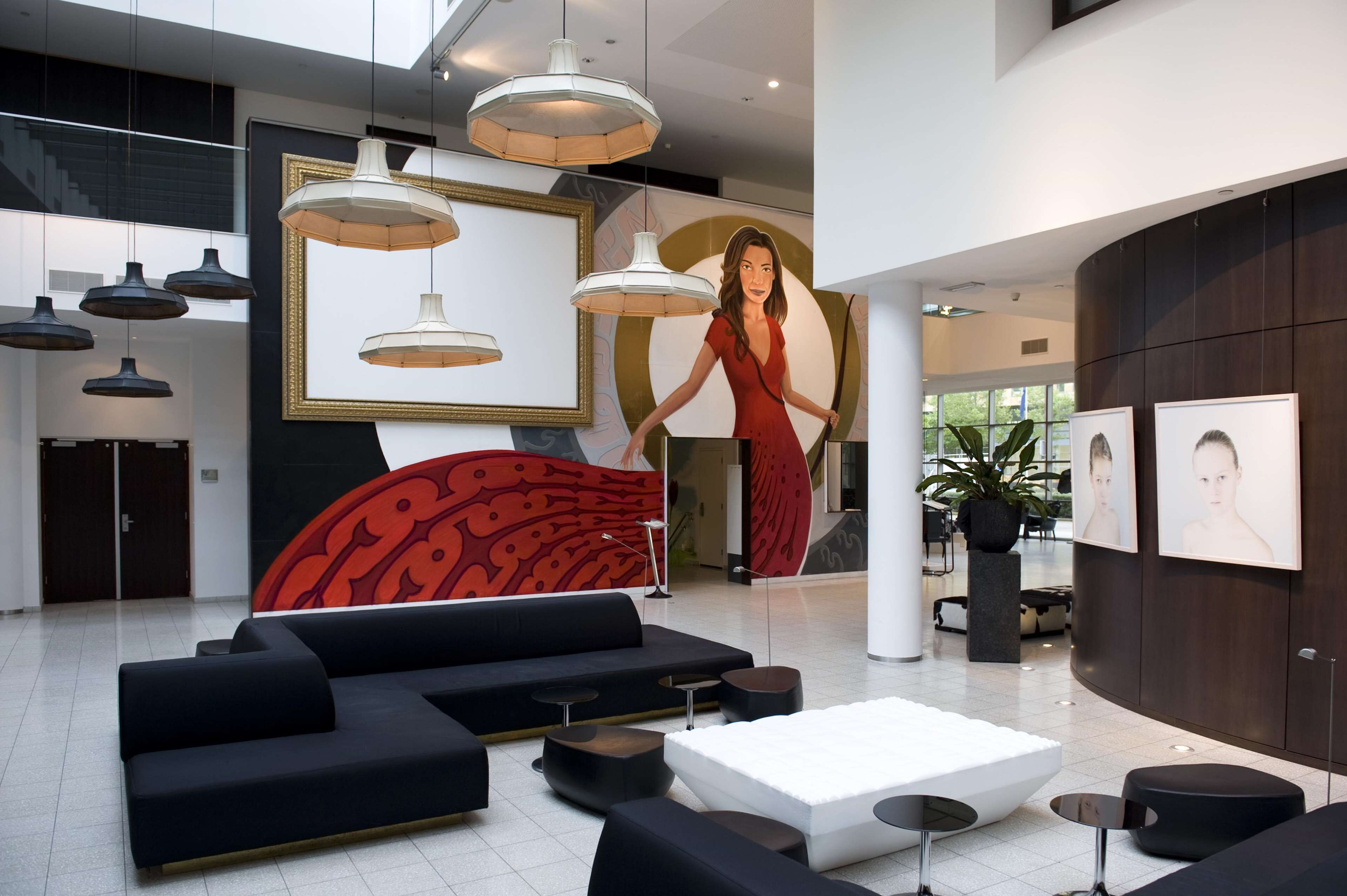 A modern lobby with black sofas, a white coffee table, and pendant lighting.