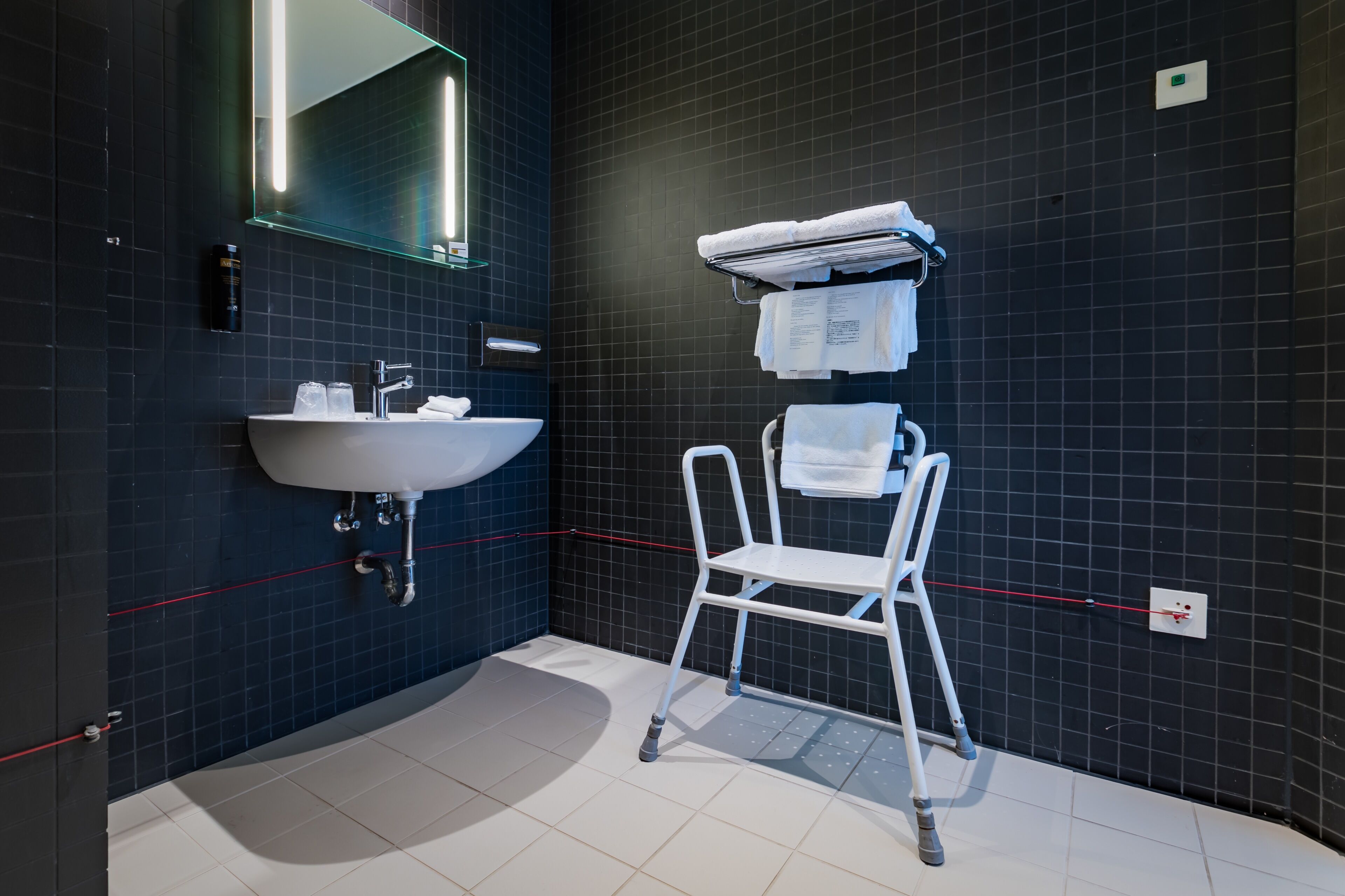 A modern bathroom with a white sink, mirror, and towel rack.