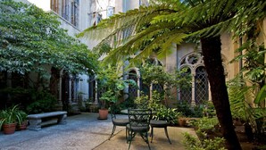 A courtyard with a stone bench, a table with chairs, and various potted plants. - Berkeley City Club (Berkeley)