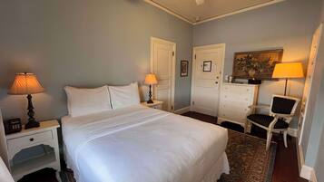 A neatly arranged bedroom with a large bed, two bedside tables with lamps, a dresser, and a chair.