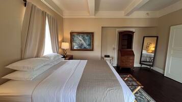 Habitación de hotel con una cama grande, un cuadro en la pared, un aparador de madera y un espejo.