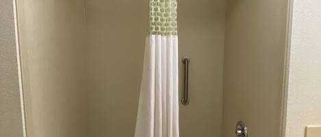 A bathroom with a bathtub, a shower curtain, and a towel on the floor.