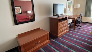 A hotel room with a bed, a TV, a desk, a chair, a dresser, and a carpeted floor. - Budget Inn San Leandro (San Leandro)