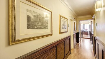 Un pasillo con fotografías en blanco y negro enmarcadas en las paredes, paneles de madera y vista a una habitación con un escritorio y una silla.